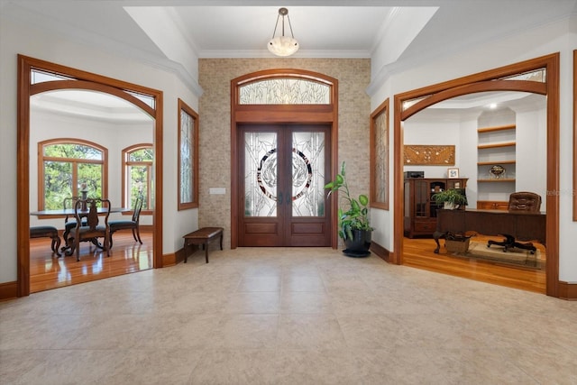 tiled entryway with ornamental molding, french doors, and a wealth of natural light