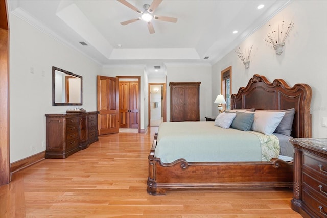 bedroom featuring light wood-style flooring, visible vents, a raised ceiling, and crown molding