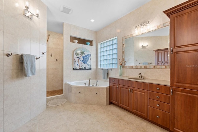 bathroom featuring a bath, vanity, tile walls, and tile patterned floors