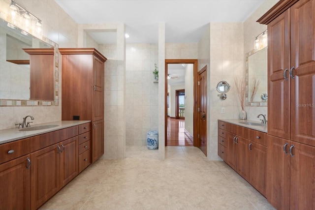 bathroom featuring two vanities, a sink, and tile walls