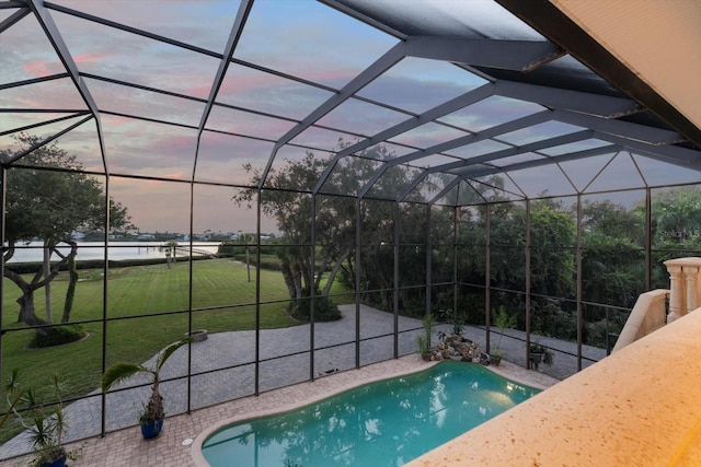 outdoor pool with glass enclosure, a lawn, and a patio