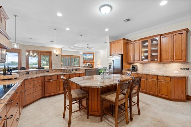 kitchen with appliances with stainless steel finishes, brown cabinetry, a kitchen bar, and a sink