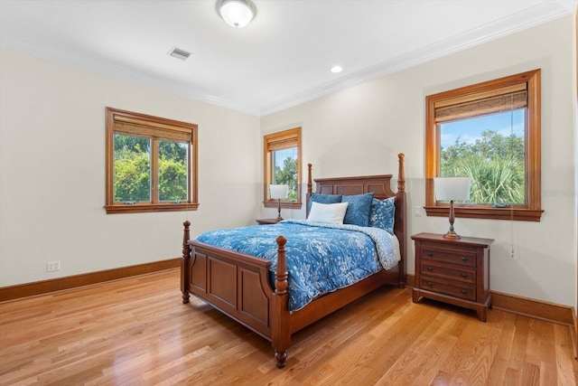 bedroom with ornamental molding, light wood-type flooring, visible vents, and baseboards