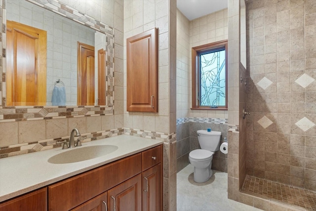 full bath with toilet, vanity, tile walls, tiled shower, and tile patterned floors