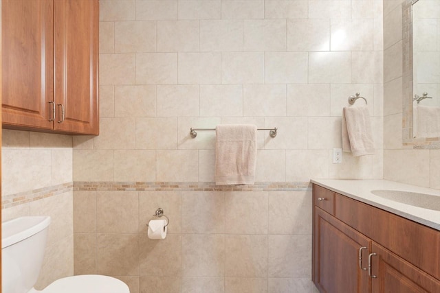 bathroom featuring toilet, vanity, and tile walls