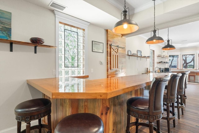 bar featuring pendant lighting, dark wood finished floors, visible vents, ornamental molding, and wet bar