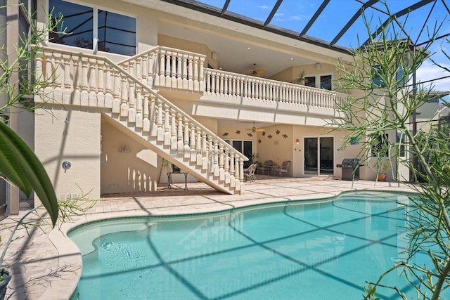 outdoor pool featuring a ceiling fan, glass enclosure, a patio area, and stairs