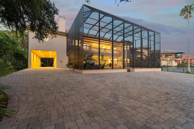 exterior space featuring a lanai, a chimney, and stucco siding