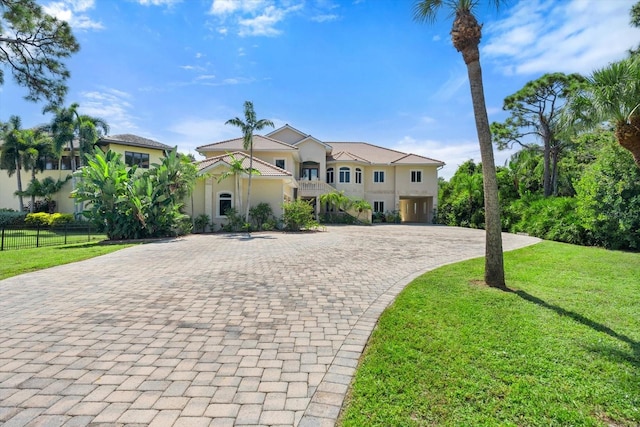 view of front of house featuring a front lawn, decorative driveway, and a balcony