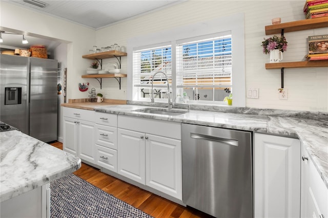 kitchen with wood finished floors, open shelves, appliances with stainless steel finishes, and a sink