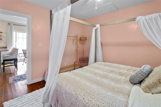 bedroom featuring attic access, baseboards, ceiling fan, wood finished floors, and a closet