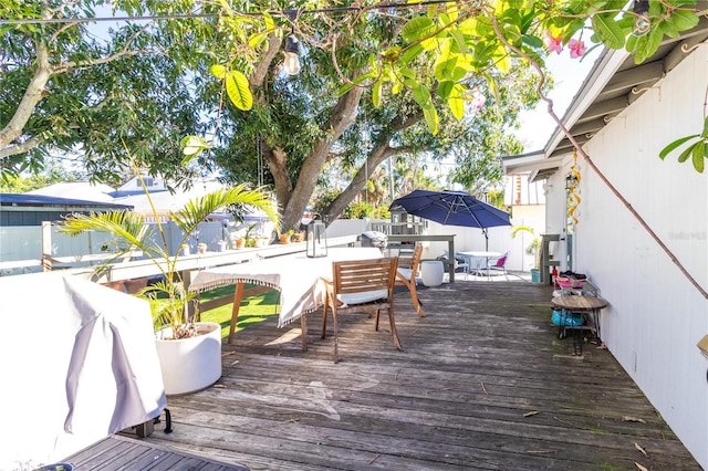 wooden terrace with outdoor dining area, fence, and area for grilling