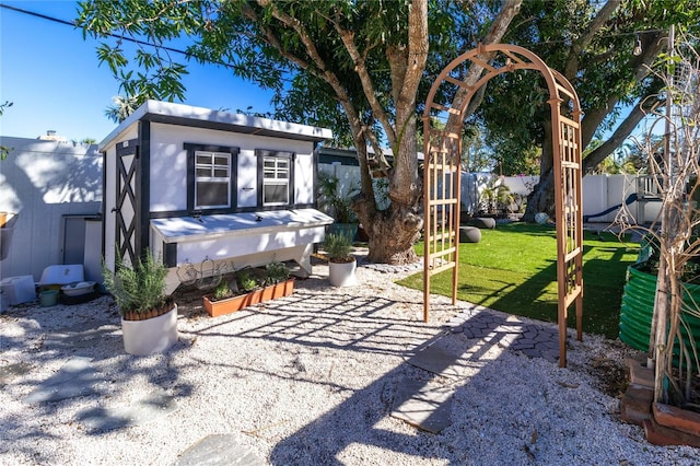 exterior space featuring a patio area, a fenced backyard, an outdoor structure, and a lawn