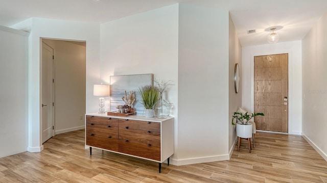 hallway featuring visible vents, baseboards, and light wood-style floors