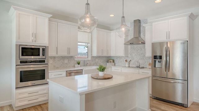 kitchen with decorative backsplash, light wood-style flooring, appliances with stainless steel finishes, and wall chimney range hood