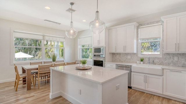 kitchen with a sink, decorative backsplash, appliances with stainless steel finishes, and white cabinetry