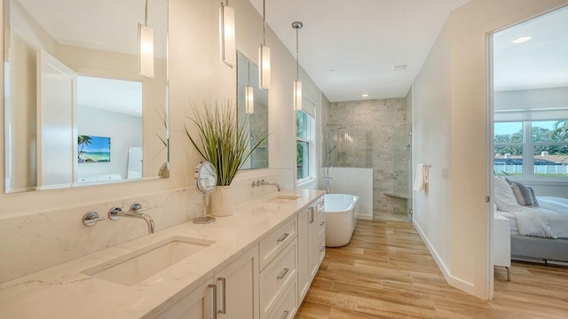 ensuite bathroom featuring a soaking tub, wood finished floors, a tile shower, and a sink