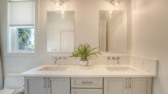 bathroom with double vanity, toilet, and a sink