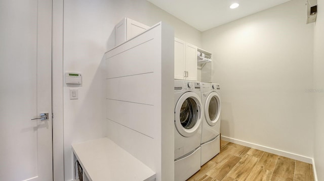 clothes washing area featuring washing machine and clothes dryer, baseboards, recessed lighting, light wood-style flooring, and cabinet space