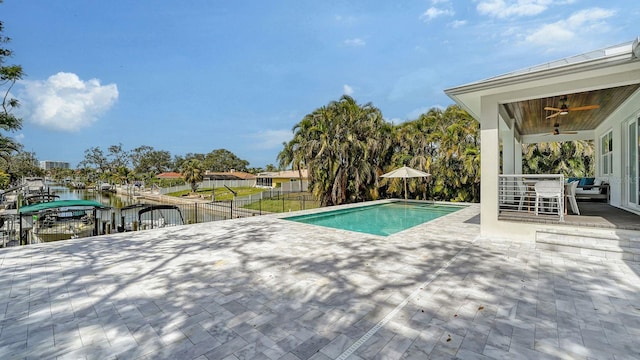 view of pool with a boat dock, a ceiling fan, fence, a fenced in pool, and a patio area