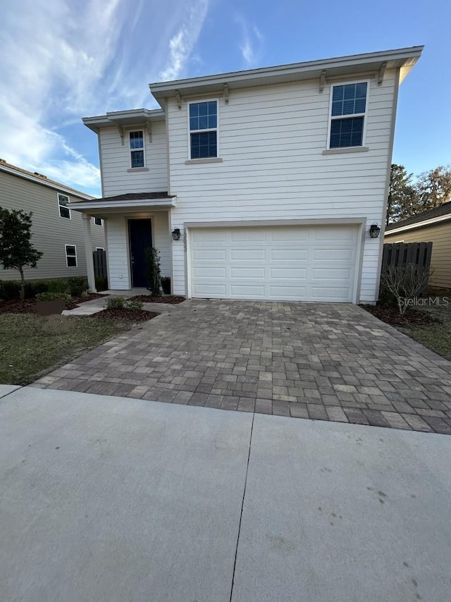 traditional-style home with a garage and decorative driveway