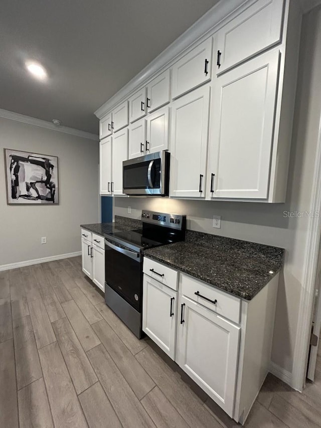 13633 NW 14th Pl, Newberry, FL 32669 - kitchen with stainless steel appliances, white cabinetry, light wood-style floors, dark stone counters, and crown molding