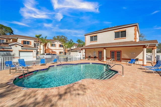 community pool featuring french doors, a patio area, and fence