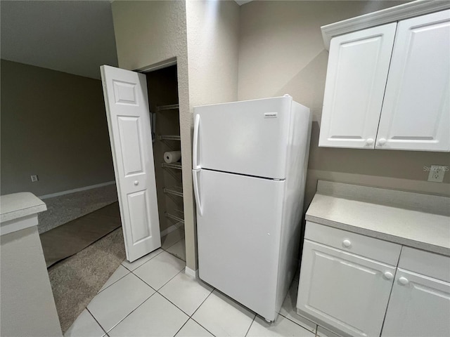 kitchen with light tile patterned floors, white cabinetry, light countertops, and freestanding refrigerator