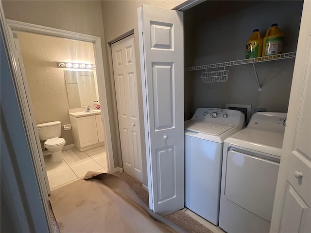 washroom featuring laundry area, separate washer and dryer, a sink, and light tile patterned flooring