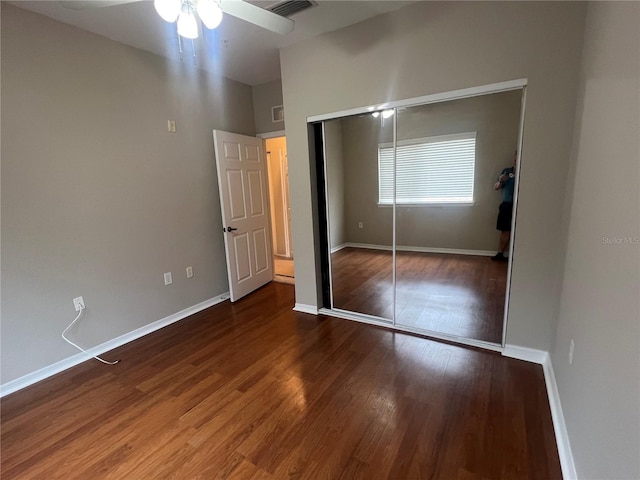 unfurnished bedroom featuring baseboards, a closet, visible vents, and wood finished floors