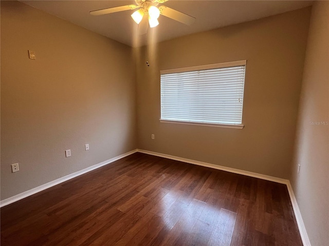 empty room with dark wood-style floors, a ceiling fan, and baseboards