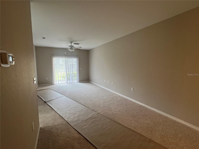 spare room featuring carpet, ceiling fan, and baseboards