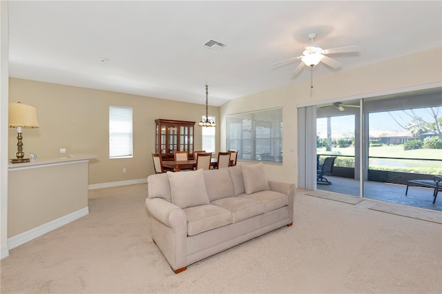 living area featuring baseboards, ceiling fan with notable chandelier, visible vents, and light colored carpet