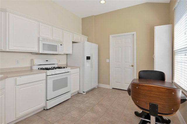 kitchen with light tile patterned floors, white appliances, white cabinetry, baseboards, and light countertops