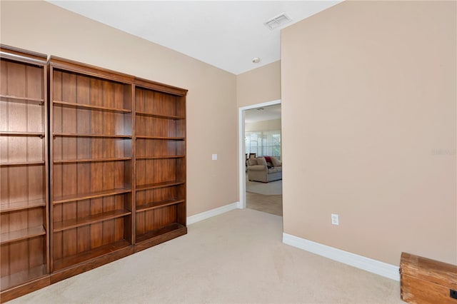 spare room with carpet flooring, visible vents, and baseboards