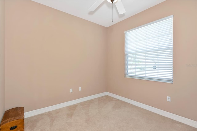 spare room with light carpet, ceiling fan, and baseboards