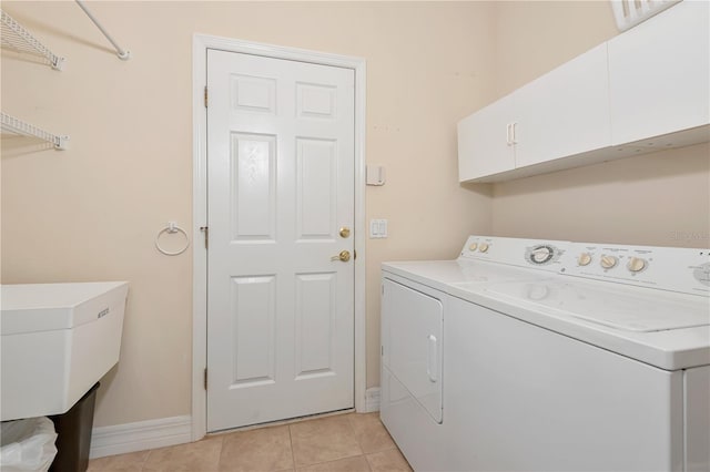 laundry area featuring baseboards, cabinet space, separate washer and dryer, and light tile patterned floors