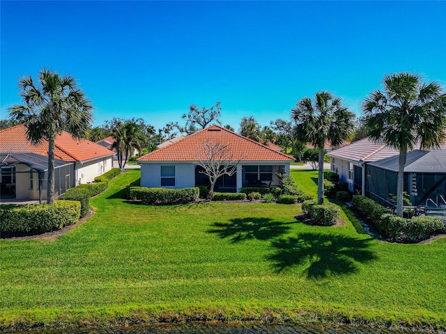 back of property with a lanai, a yard, a tiled roof, and stucco siding