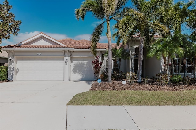 mediterranean / spanish-style home with stucco siding, a tiled roof, driveway, and a garage