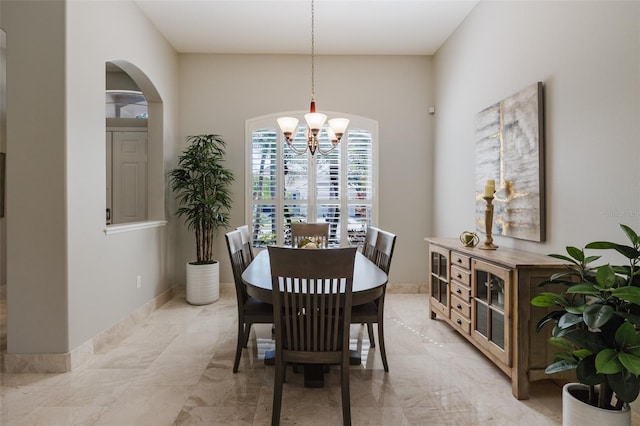 dining room with baseboards, arched walkways, marble finish floor, and an inviting chandelier