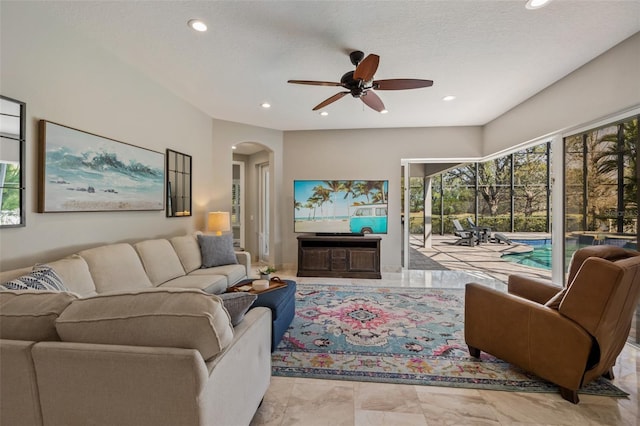 living area with recessed lighting, plenty of natural light, a ceiling fan, and arched walkways