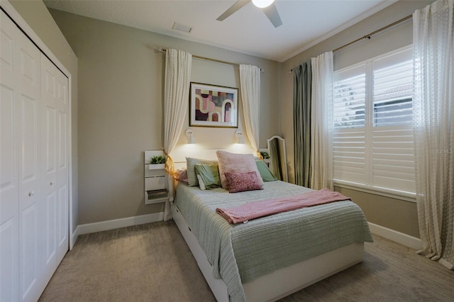 carpeted bedroom with a closet, baseboards, visible vents, and ceiling fan