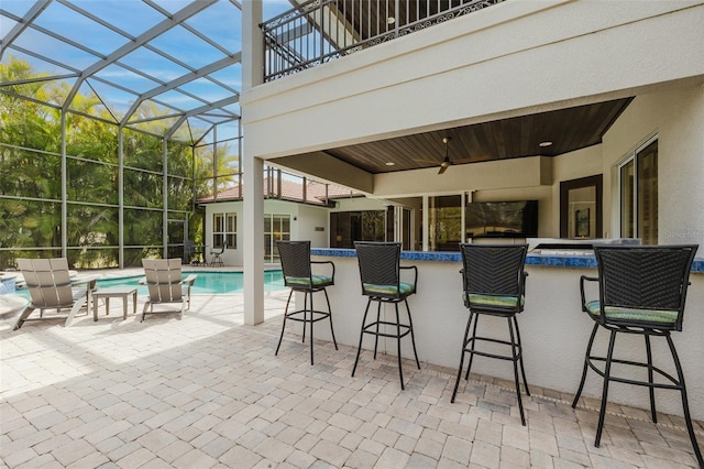 view of patio / terrace featuring glass enclosure, a balcony, an outdoor pool, and outdoor dry bar