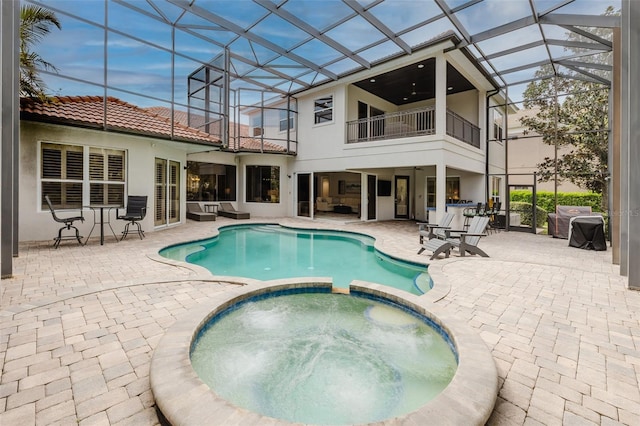 view of swimming pool with glass enclosure, a patio area, and a pool with connected hot tub