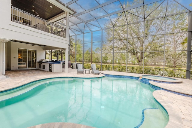 view of pool with area for grilling, a ceiling fan, a pool with connected hot tub, a patio, and glass enclosure