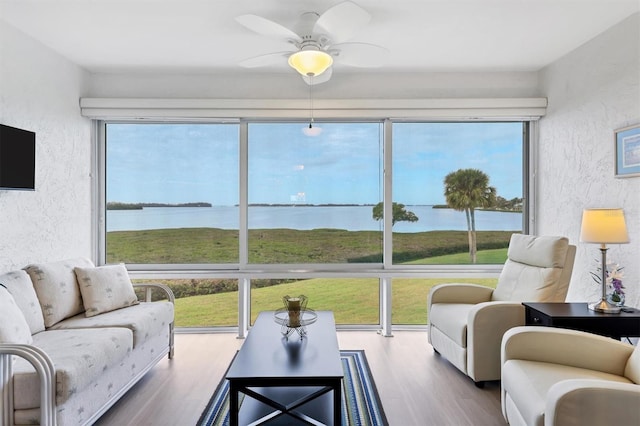 sunroom with a water view and ceiling fan