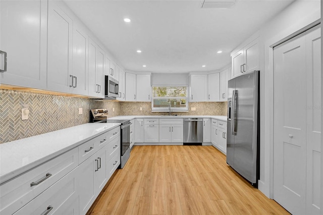 kitchen with visible vents, tasteful backsplash, white cabinetry, appliances with stainless steel finishes, and light countertops