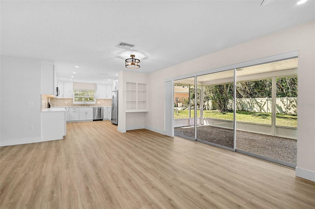 unfurnished living room featuring light wood-type flooring, visible vents, baseboards, and recessed lighting