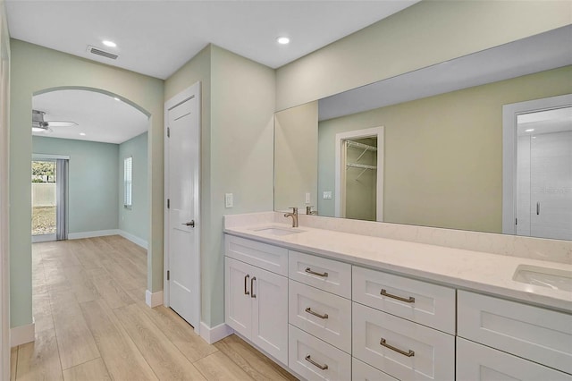 full bath with double vanity, wood finished floors, visible vents, and a sink