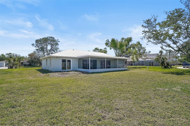 back of property featuring a yard, a sunroom, and metal roof